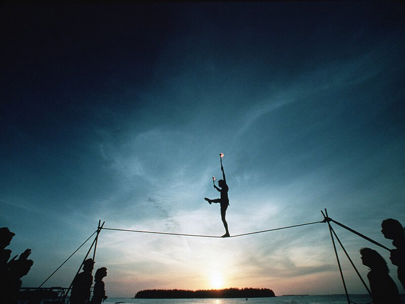 Silhouette of tightrope walker at sunset