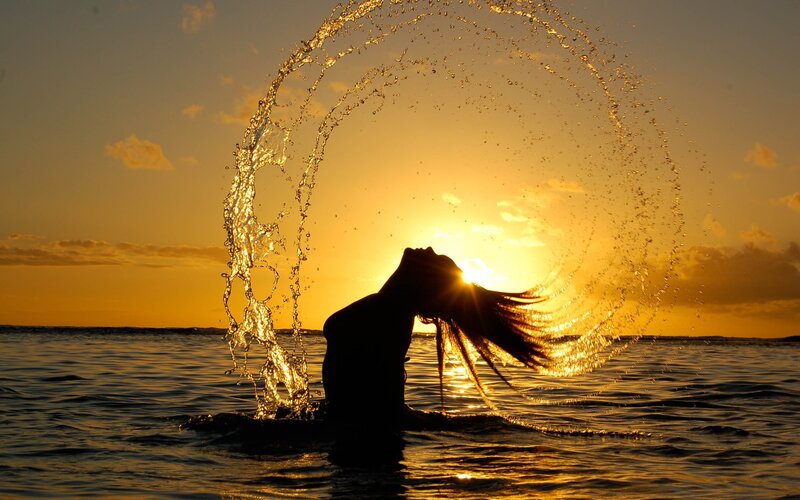 silhouette of woman in ocean at sunset