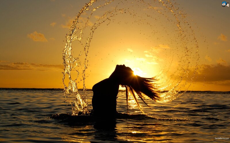 Silhouette of woman in ocean at sunset