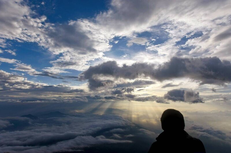 Silhouette overlooking clouds at sunrise