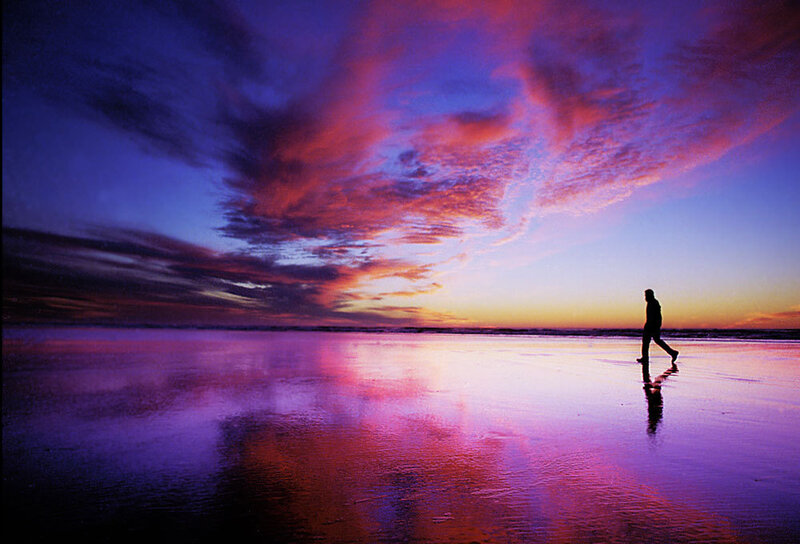 Silhouette walking on beach at sunset