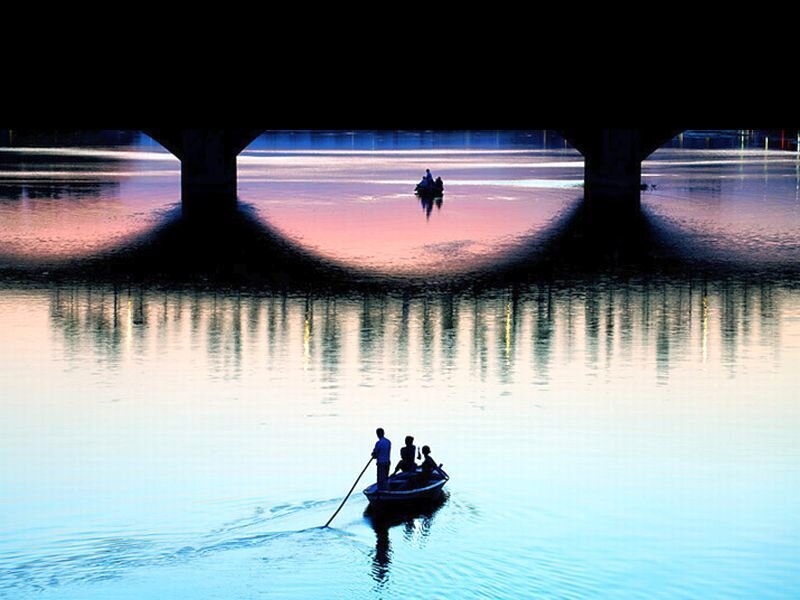 Silhouetted Boat under Bridge