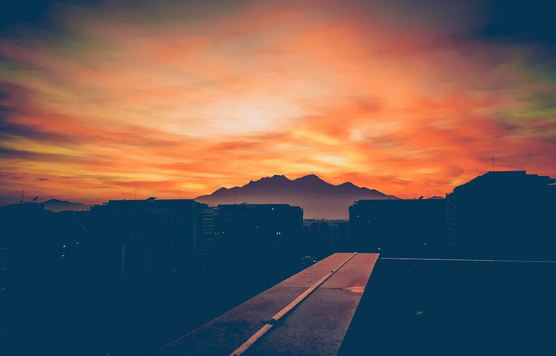 Silhouetted Buildings at Sunset — Orange, Dramatic, Photograph, Mountains