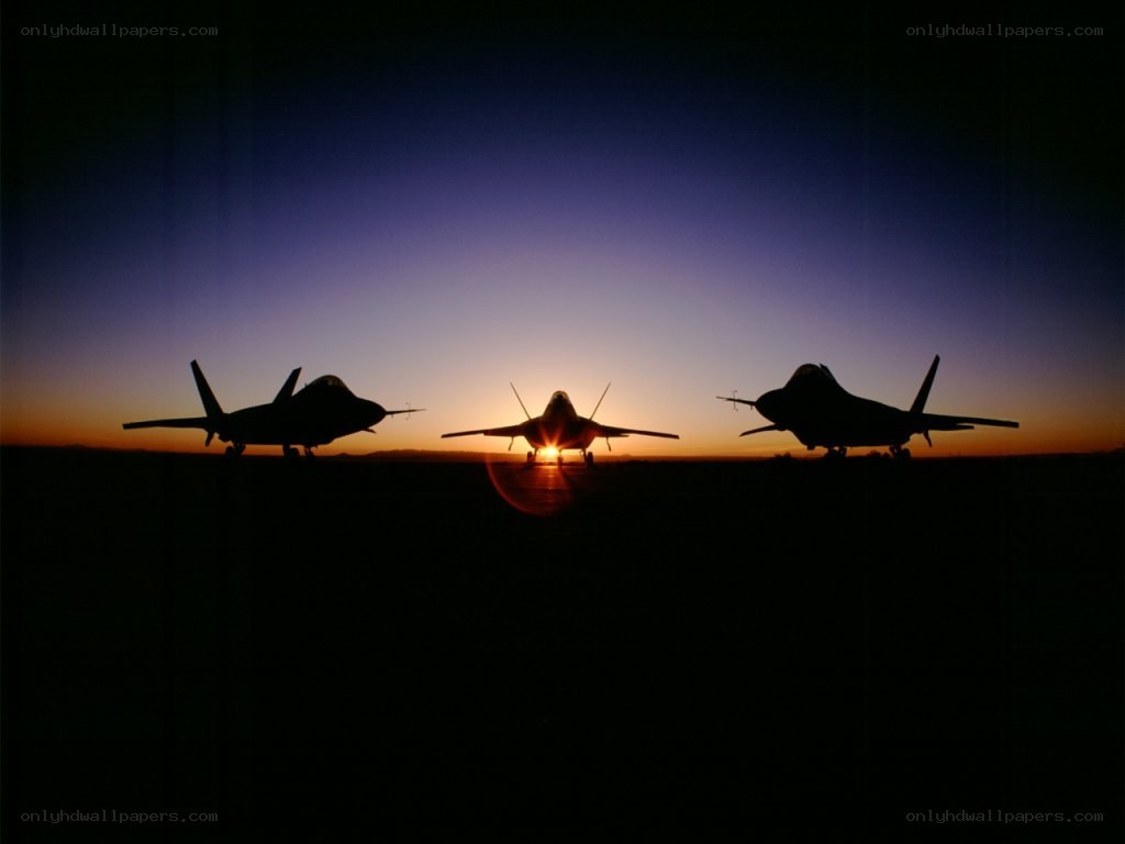 Silhouetted fighter jets at sunset