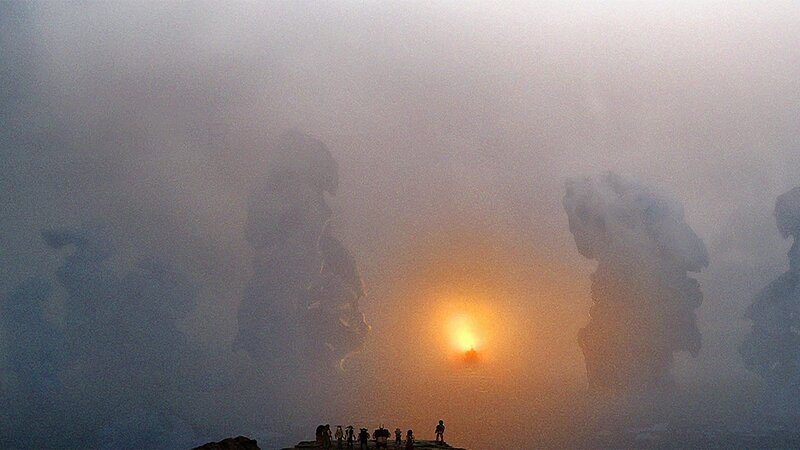 Silhouetted Figures on Cliff — Orange