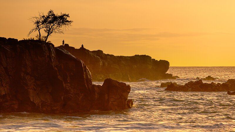 Silhouetted Figures on Rocks — Orange, Serene, Sunset