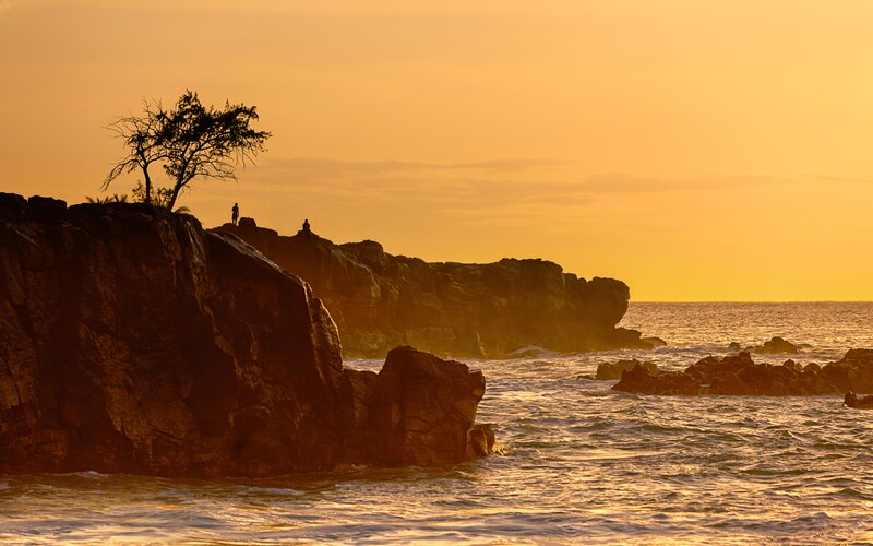 Silhouetted Figures on Rocks — Orange, Serene