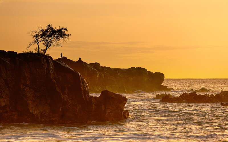 Silhouetted Figures on Rocks — Orange
