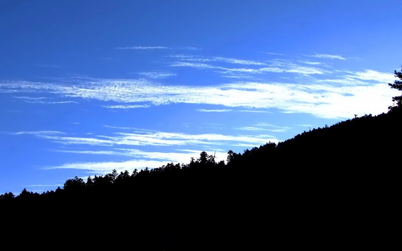 Silhouetted hill under blue sky