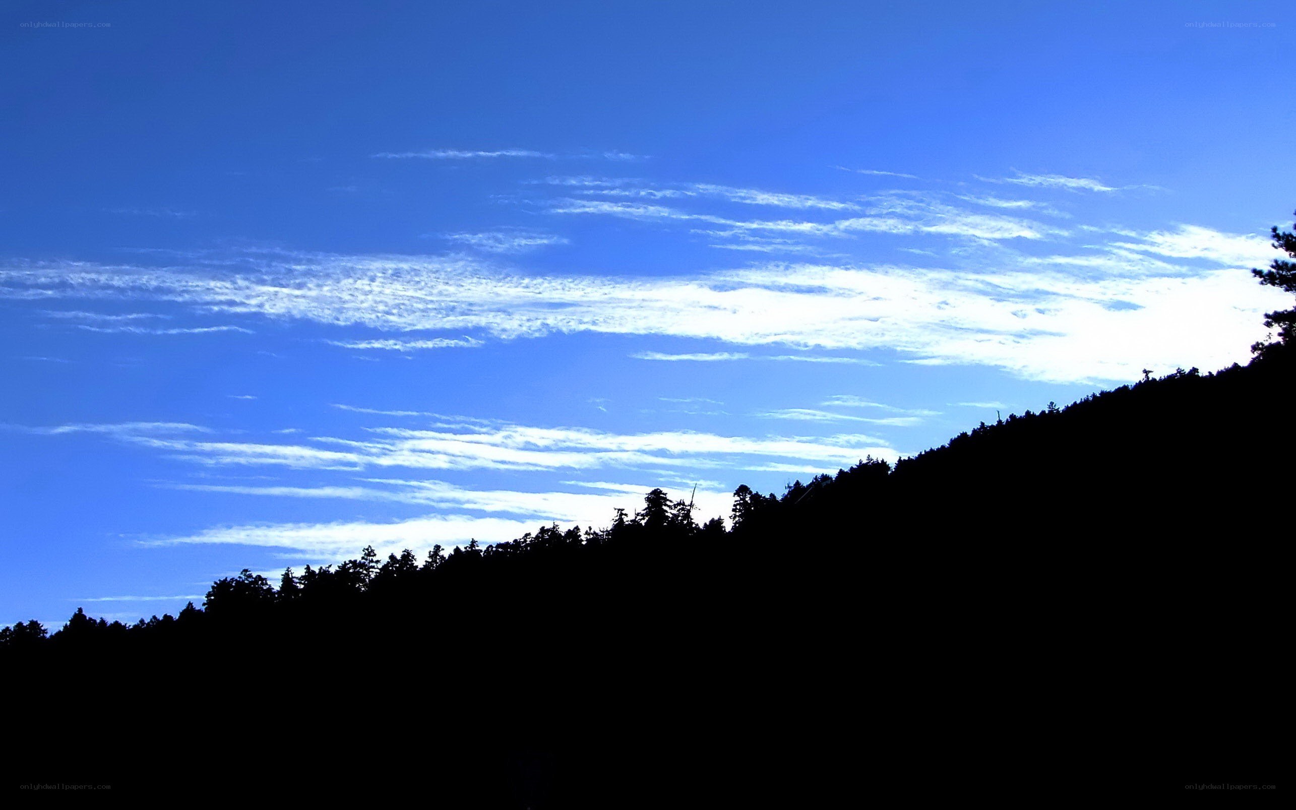 Silhouetted hill under blue sky
