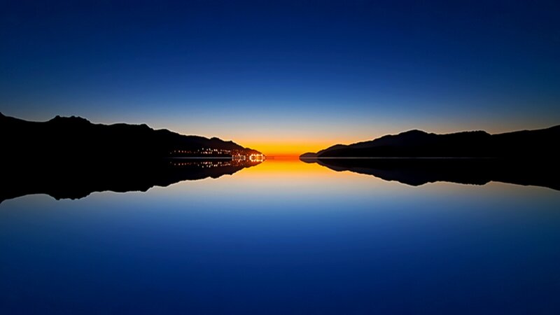 Silhouetted Mountains at Sunset — Blue, Serene, Photograph, Lake, Town Lights