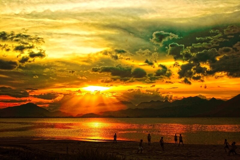 Silhouetted People on Beach — Orange, Dramatic, Sunset, Photograph, Mountains, Sun