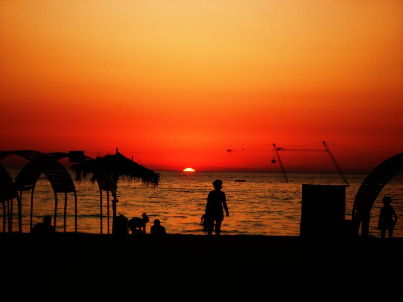 Silhouetted People on Beach — Orange, Dramatic, Sunset, Photograph, Sun, Sea, Cranes