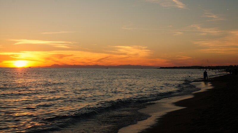 Silhouetted People on Beach — Orange, Serene, Sunset, Photograph, Ocean, Mountains