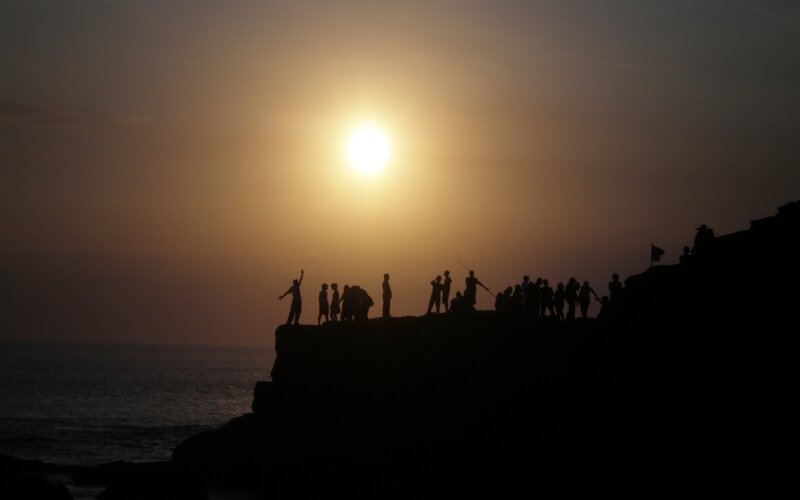Silhouetted People on Cliff — Yellow