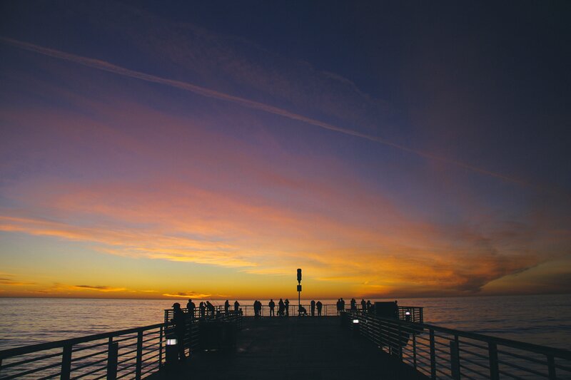 Silhouetted People on Pier — Orange, Serene, Sunset, Photograph, Sky