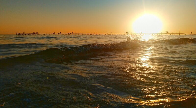 Silhouetted People on Pier — Orange, Serene, Sunset, Photograph, Sun