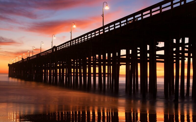 Silhouetted Pier at Sunset — Orange, Serene, Photograph, Streetlights