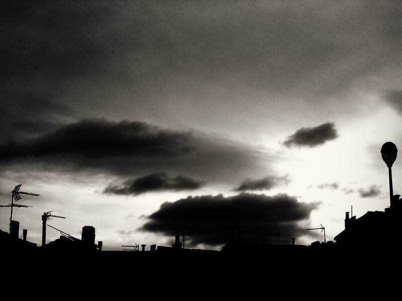 silhouetted rooftops under stormy sky