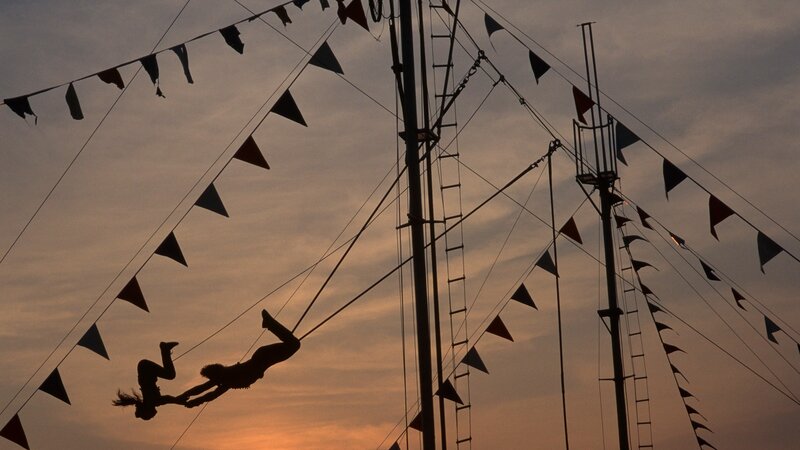 Silhouetted trapeze artists at dusk