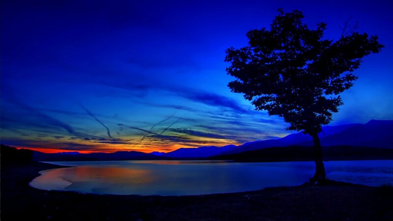 Silhouetted Tree at Lake — Blue, Serene, Sunset, Photograph, Mountains, Sky