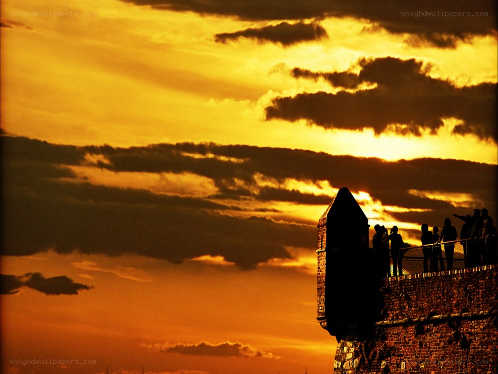 Silhouettes at sunset on a castle wall