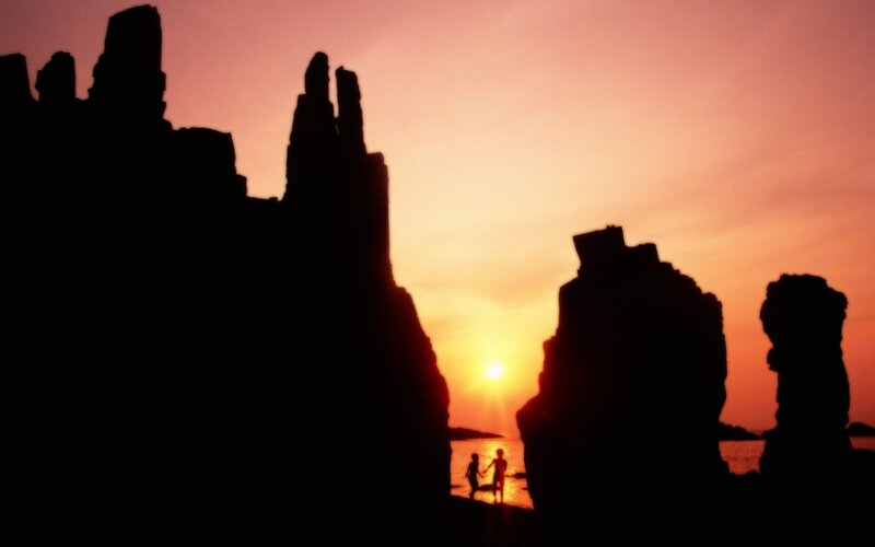 Silhouettes at sunset on a rocky shore