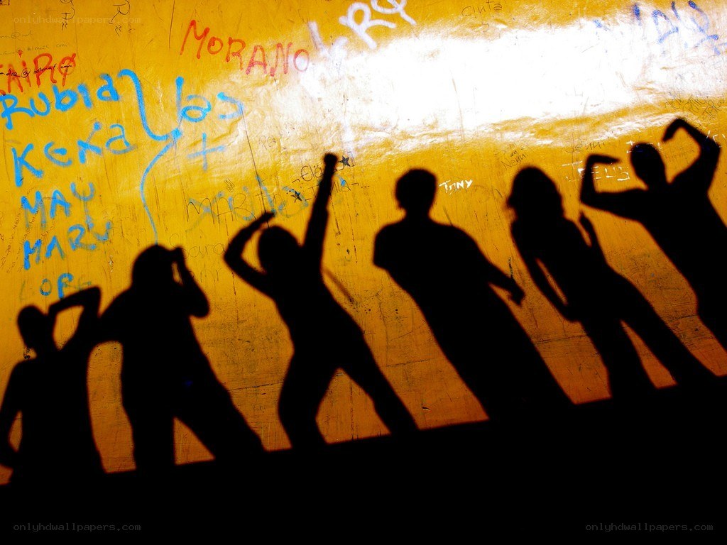 Silhouettes dancing on a graffiti wall