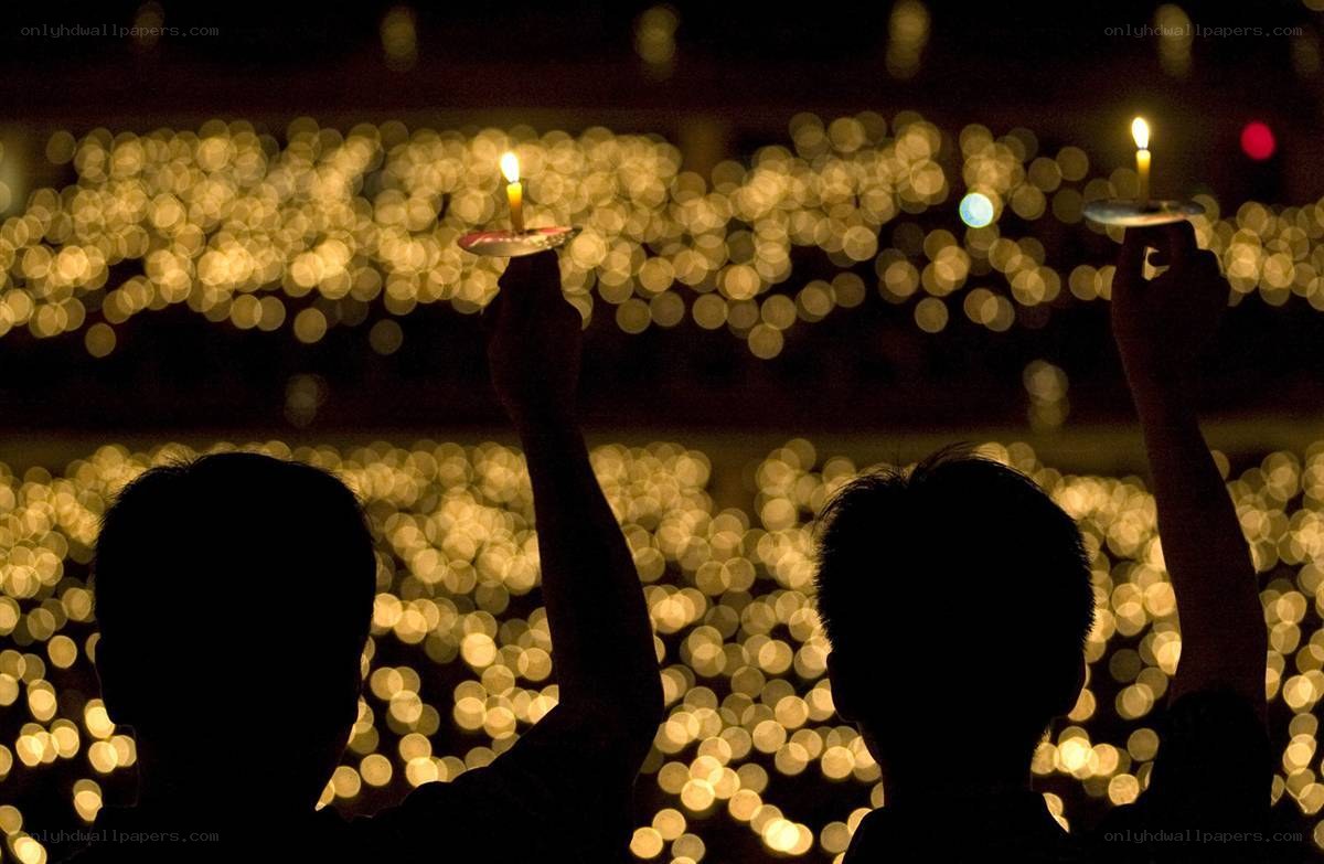 Silhouettes holding candles at night
