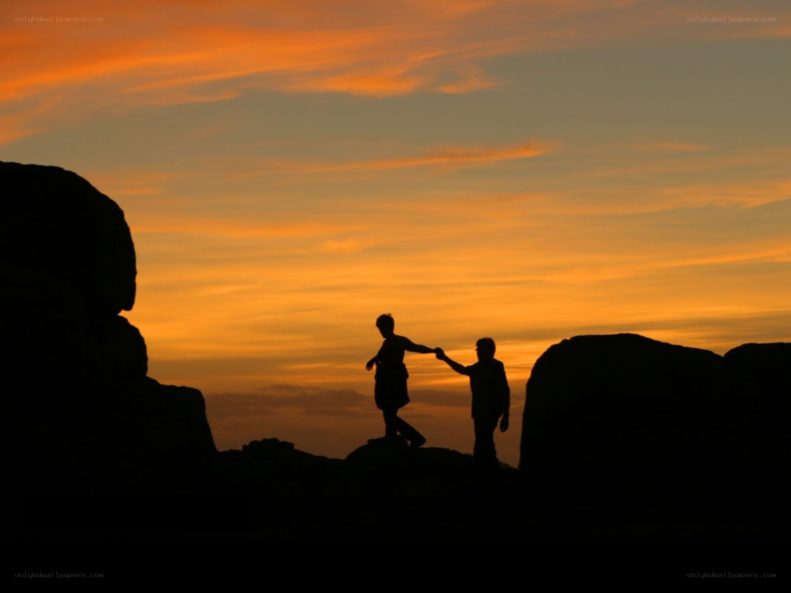 Silhouettes holding hands at sunset