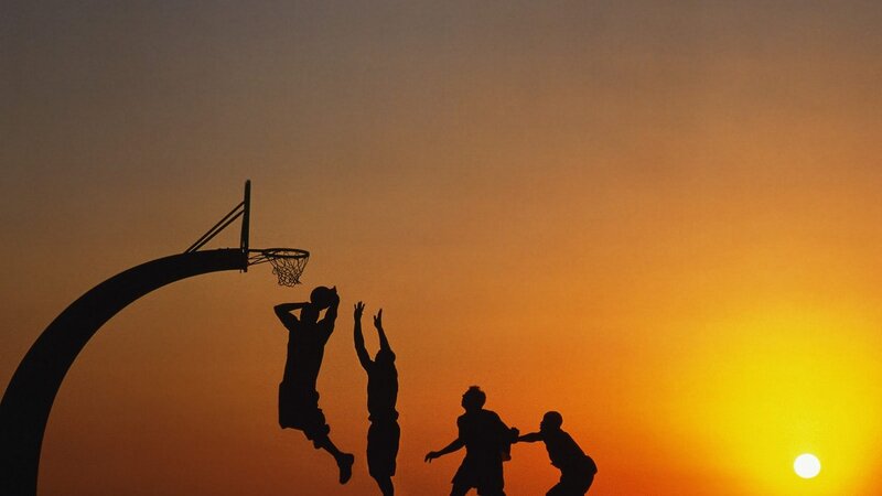 Silhouettes of basketball players at sunset