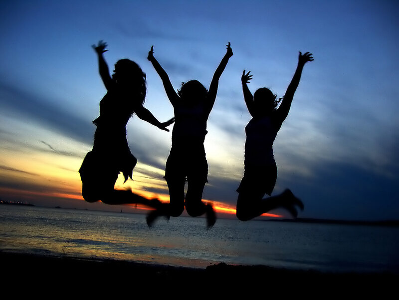 silhouettes of friends jumping at sunset