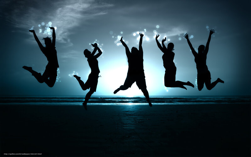 Silhouettes of people jumping on beach