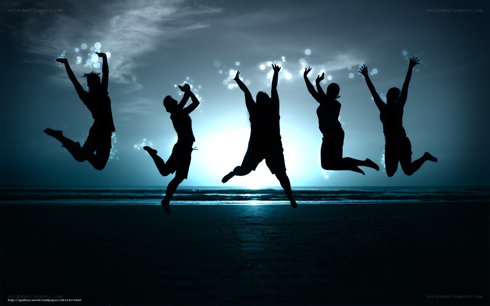 Silhouettes of people jumping on beach