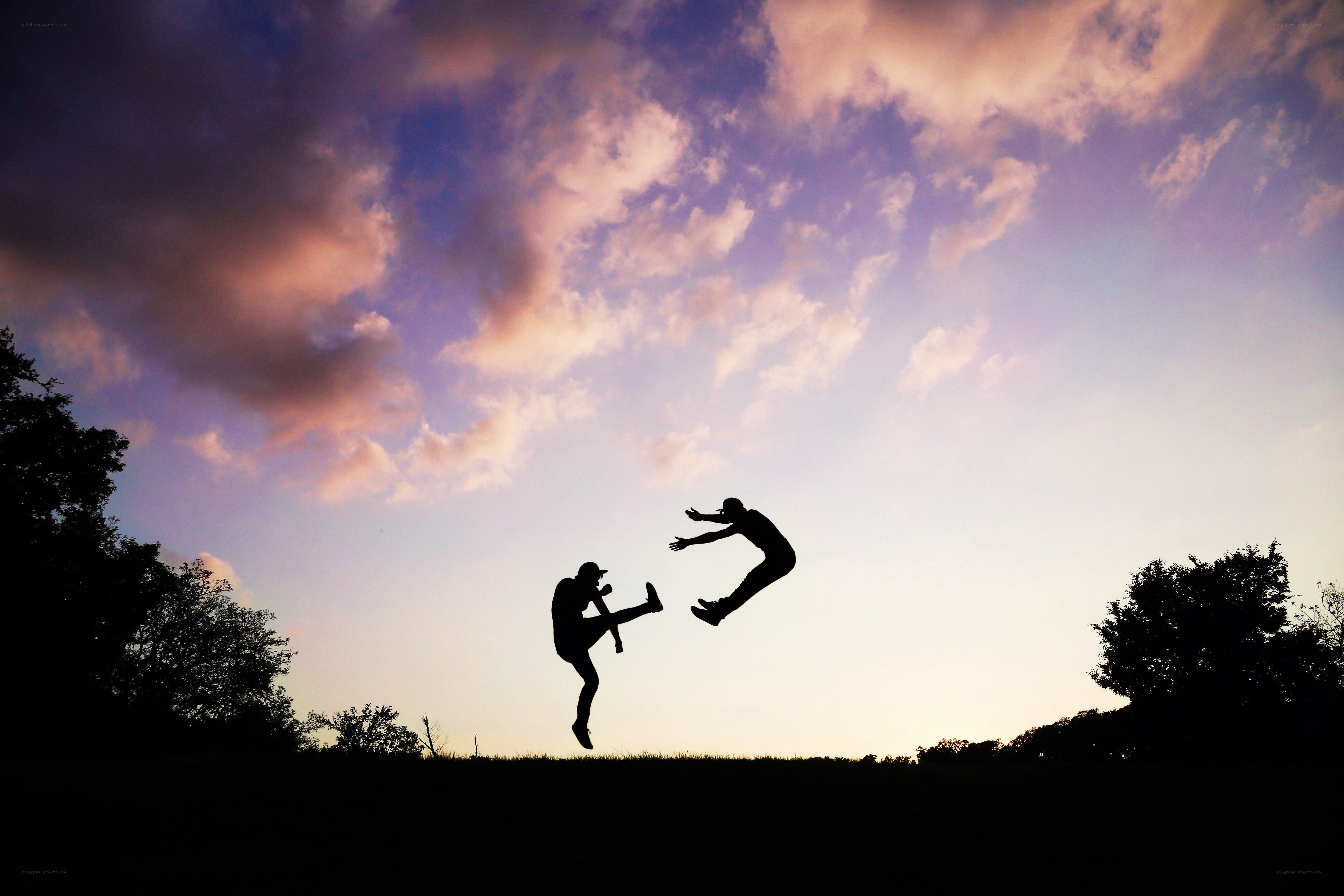 Silhouettes of two people jumping