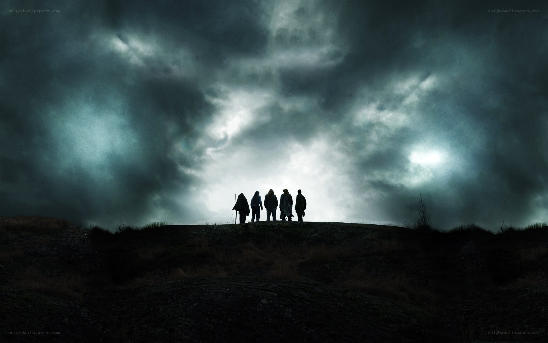 Silhouettes on a hill under stormy sky