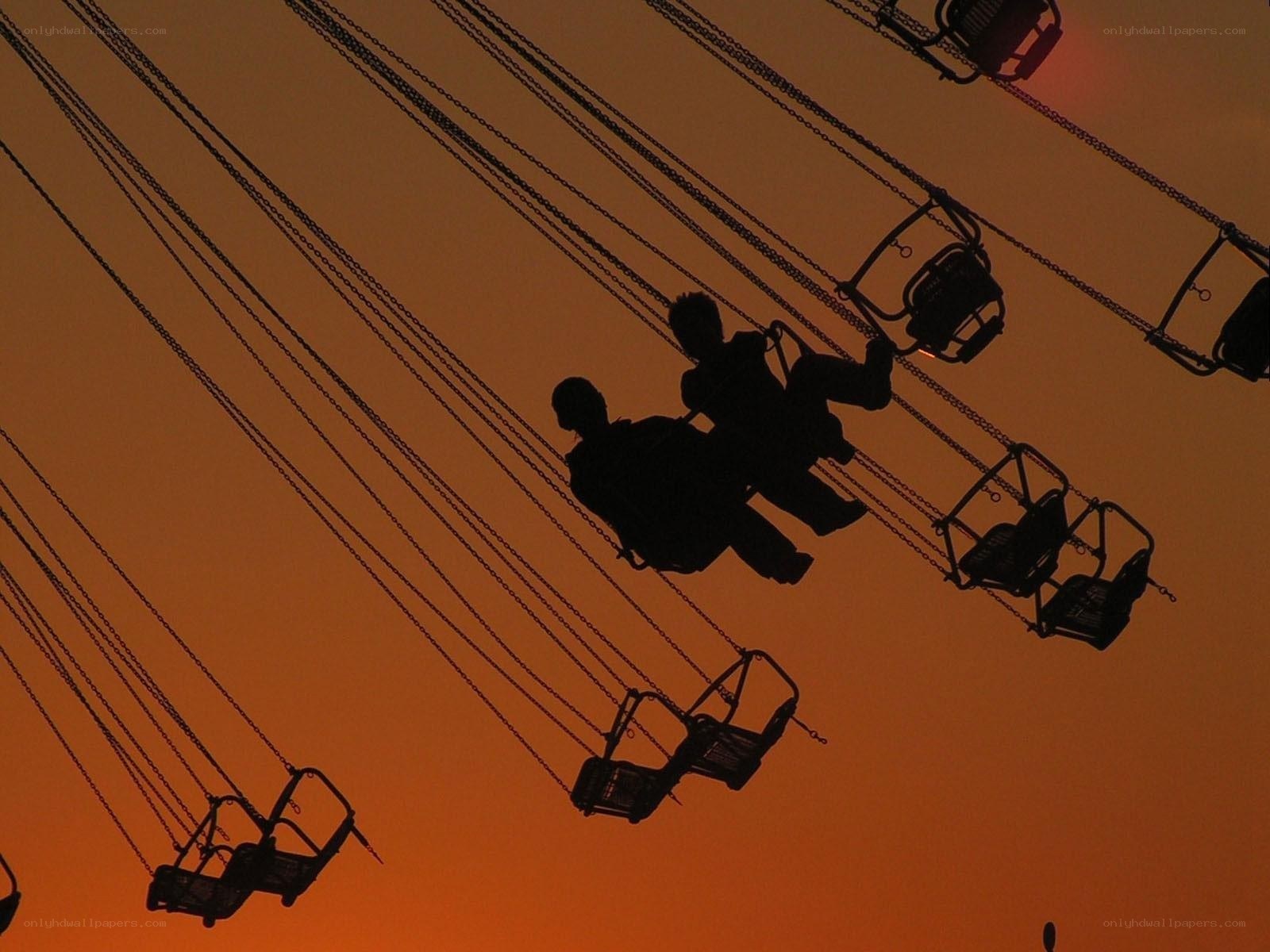 Silhouettes on a swing ride