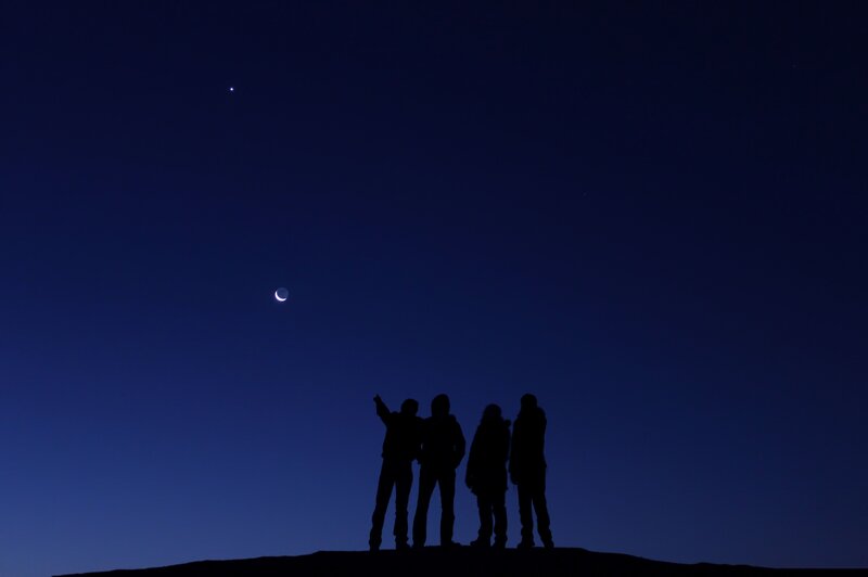 Silhouettes under the crescent moon
