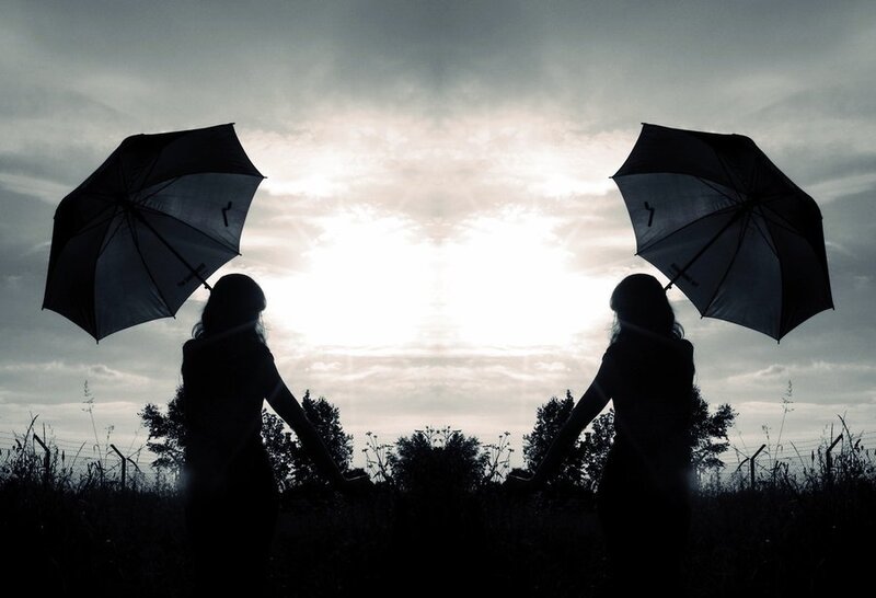 Silhouettes with umbrellas at sunset