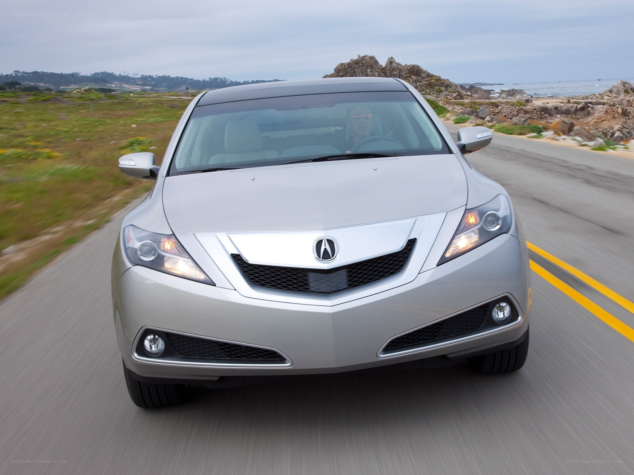 silver acura driving on coastal road