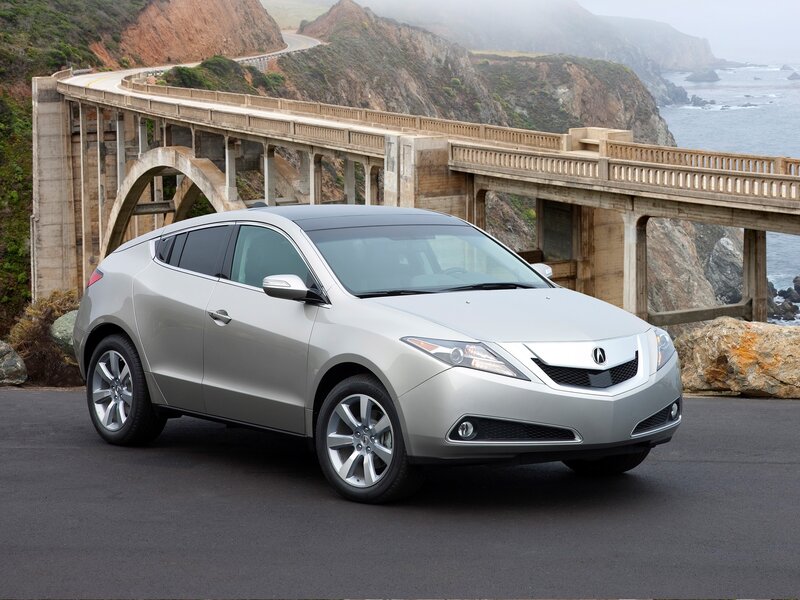 Silver Acura ZDX by a coastal bridge