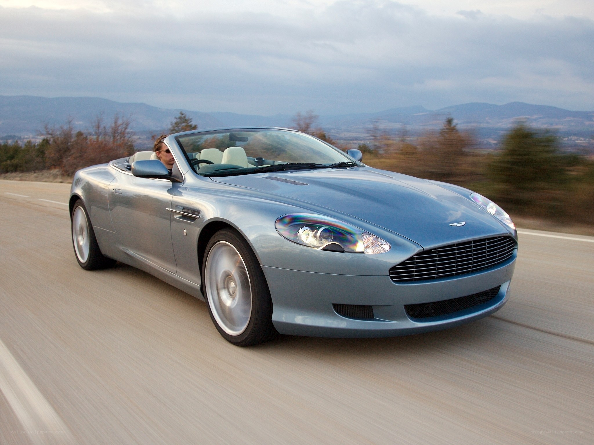 Silver Aston Martin driving on road