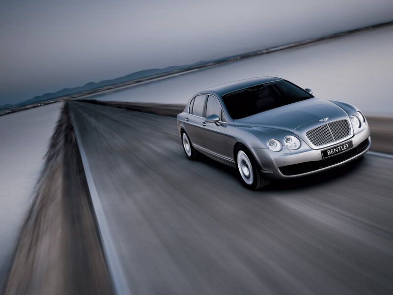Silver Bentley driving on a road