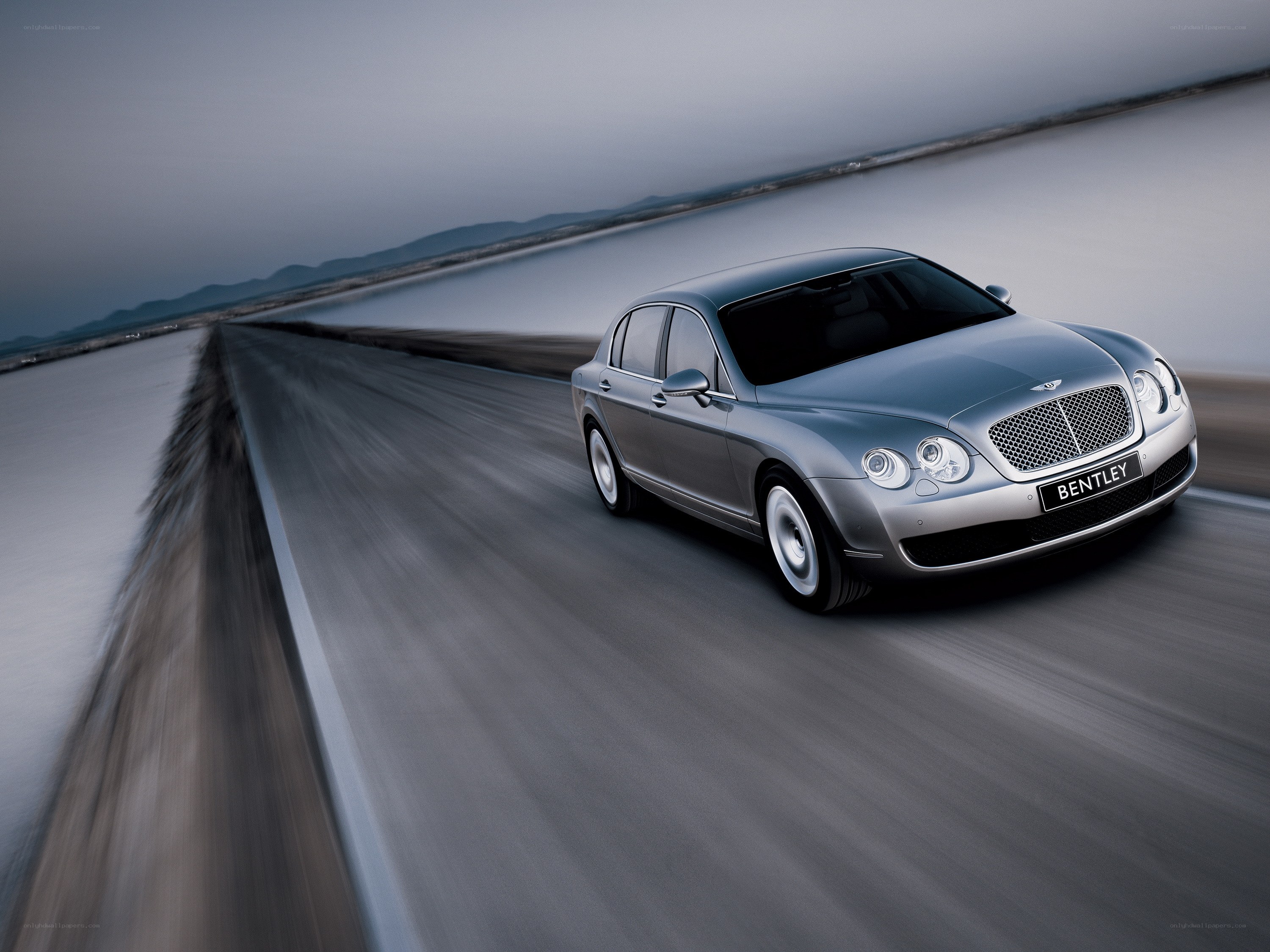 Silver Bentley driving on a road