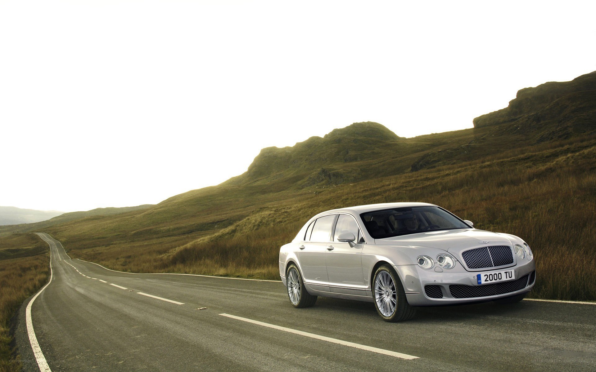Silver Bentley on a winding road