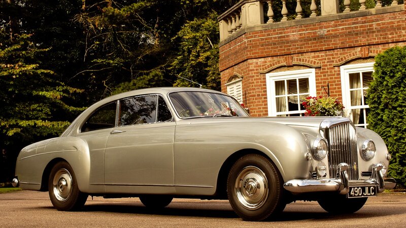 Silver Bentley parked outside a house