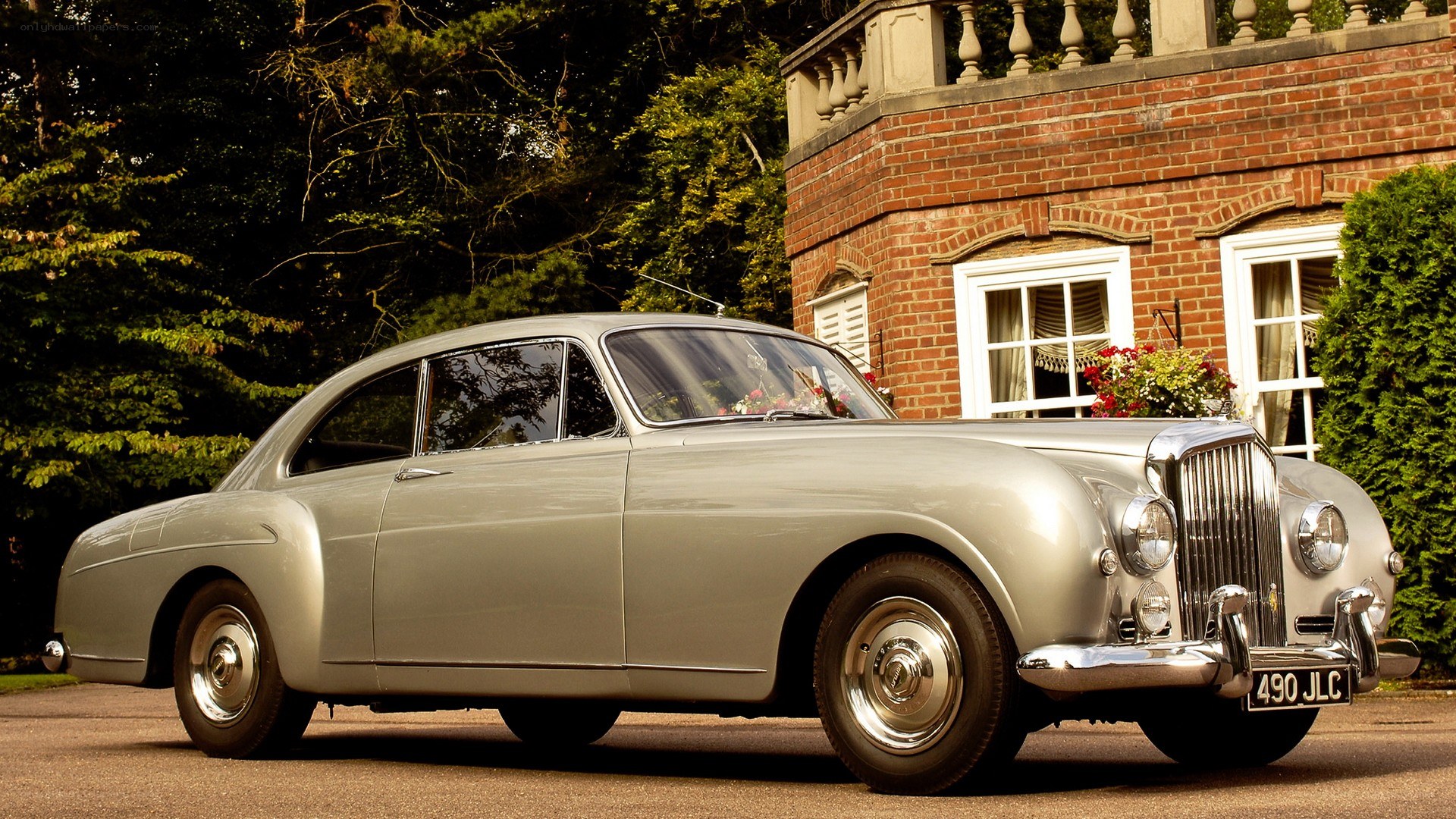 Silver Bentley parked outside a house