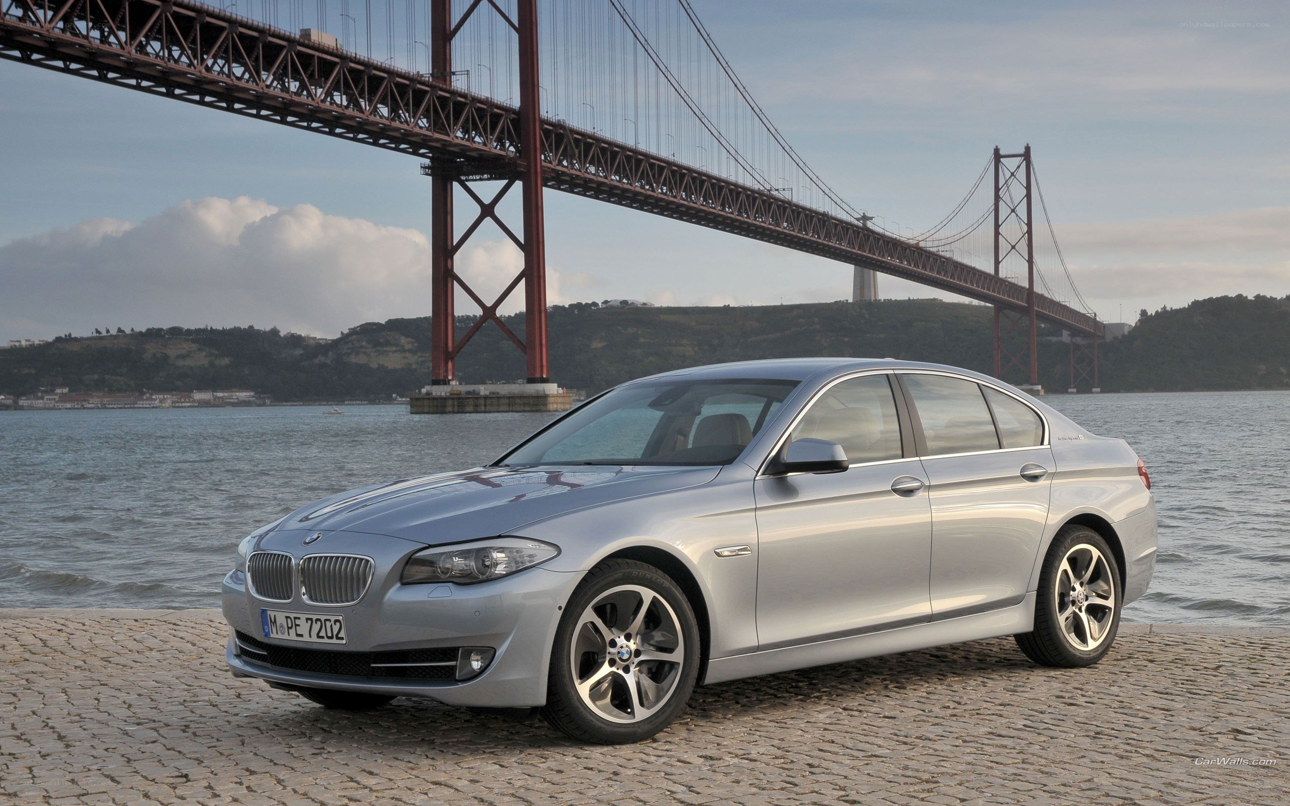 Silver BMW 5 Series by a bridge