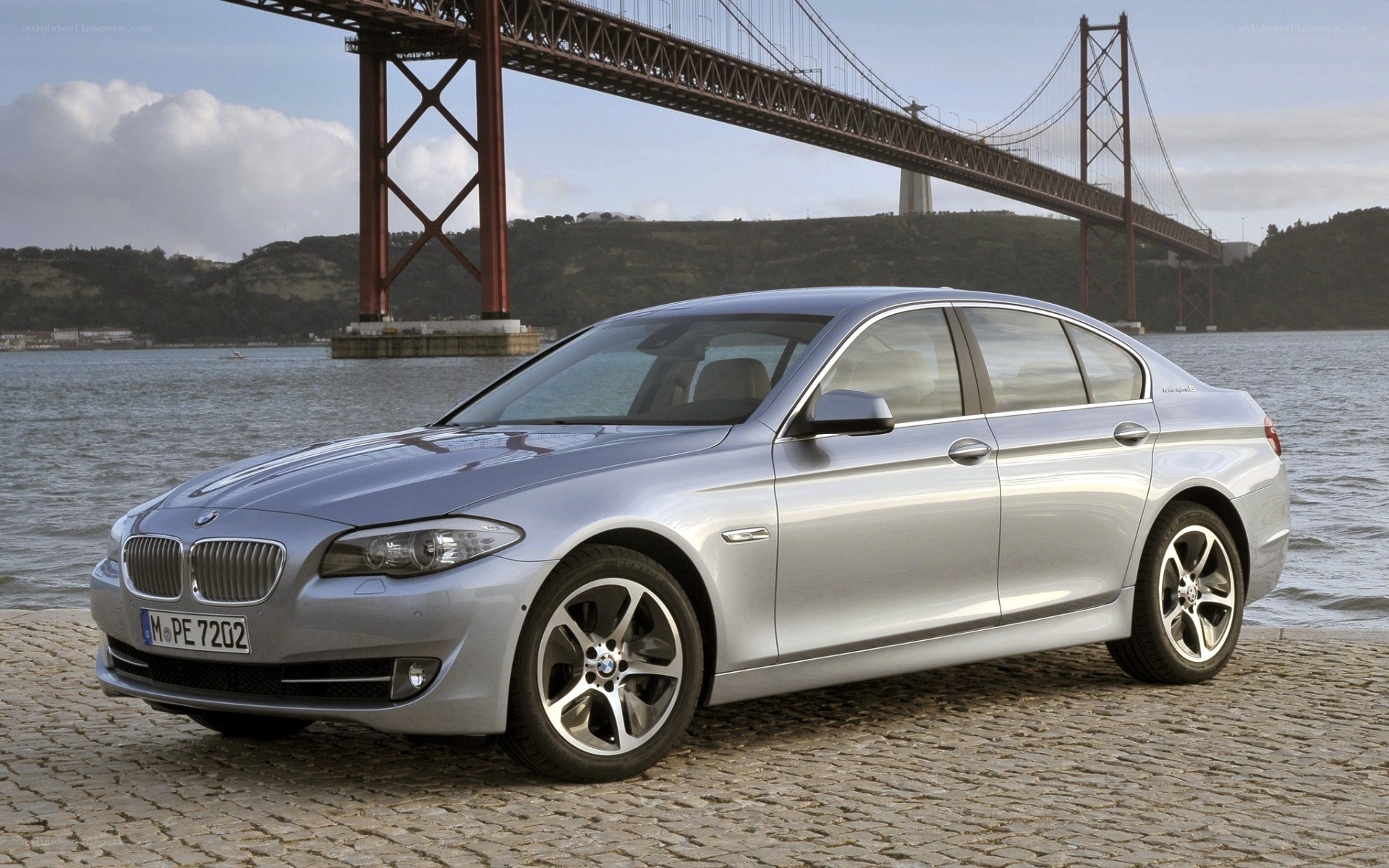 Silver BMW 5 Series by a bridge