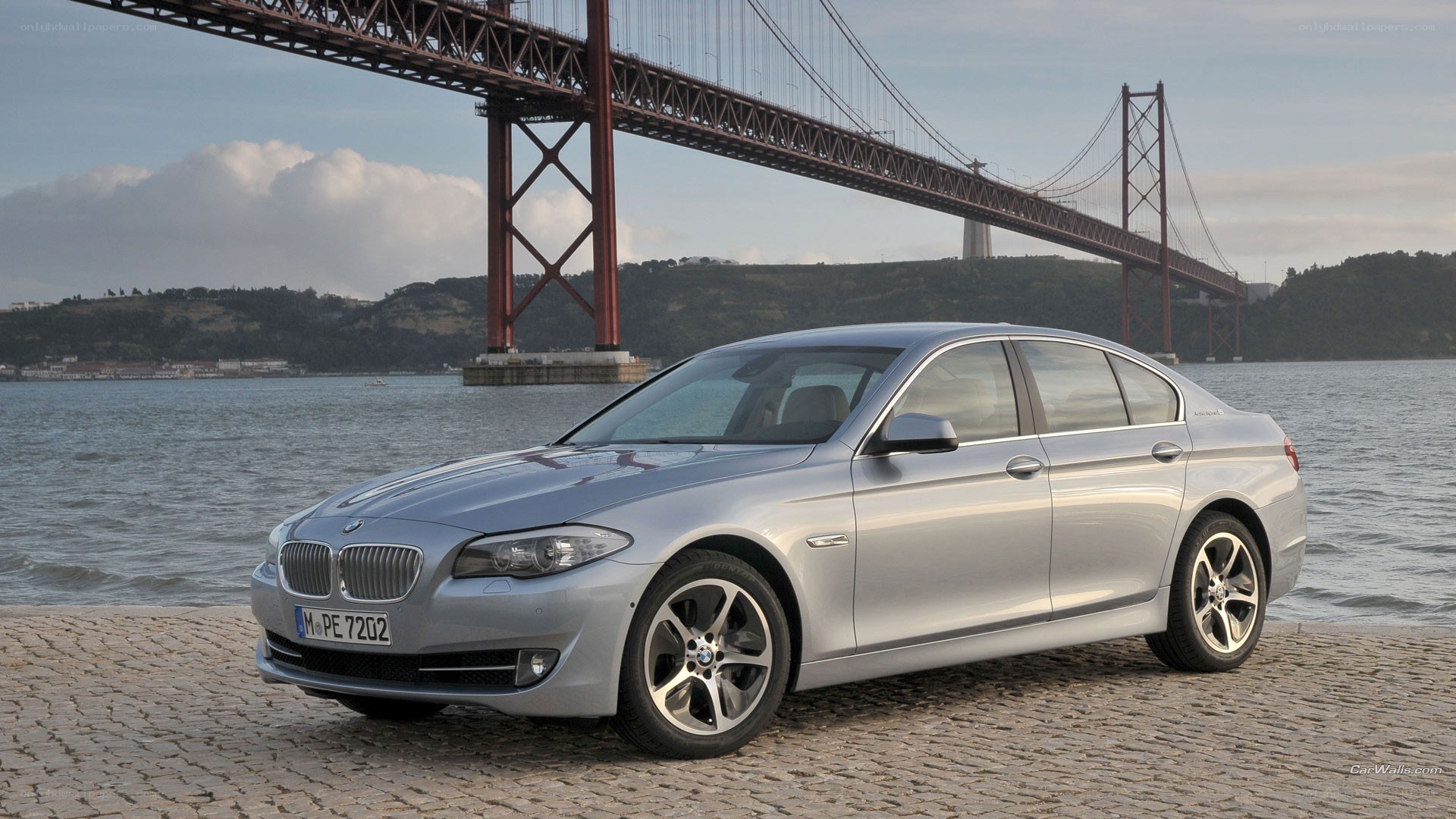 Silver BMW 5 Series by a bridge